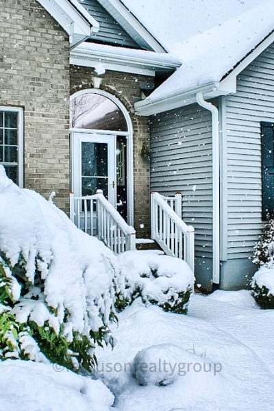 snow on a house with snow on shrubs